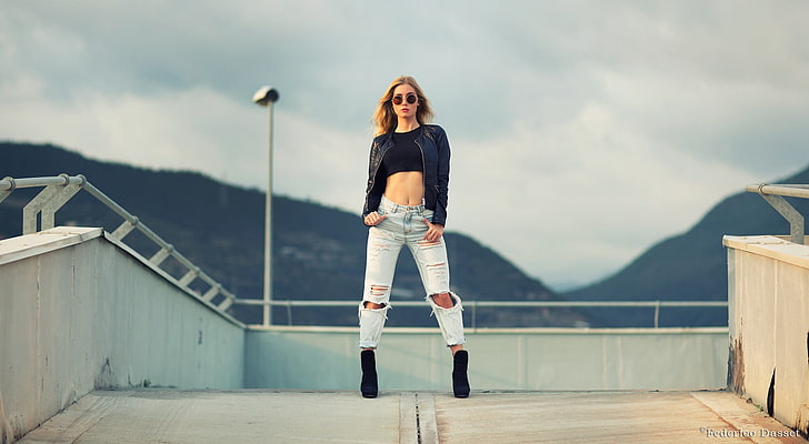 woman wearing black crop-top shirt , black zip-up jacket and blue-washed distressed jeans