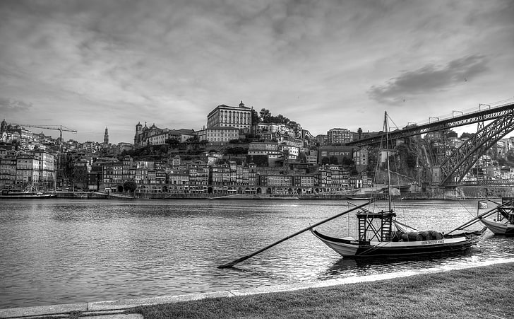 Cidade Invicta, grayscale photo of boat near bridge and village across body of water