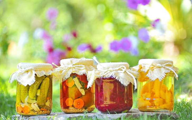 four clear glass mason jars, pickles, cucumbers, carrots, bokeh