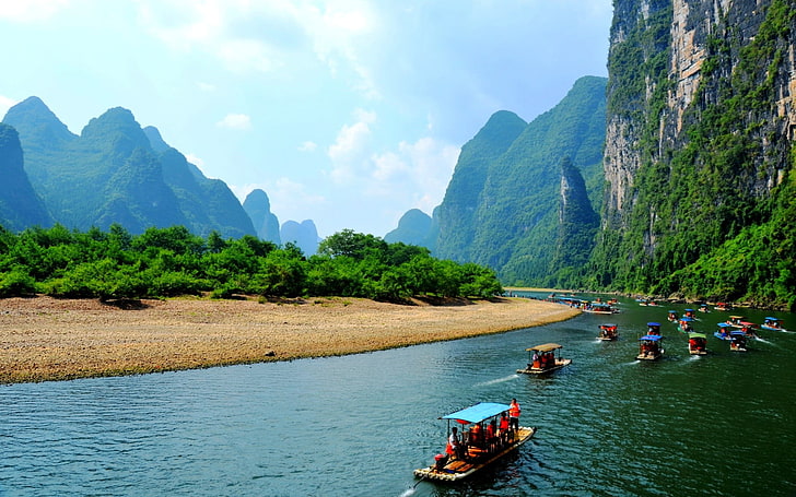 passenger boats cruising through river surrounded by mountains during daytime
