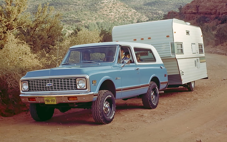 blue Chevrolet single cab truck with camper shell and RV trailer