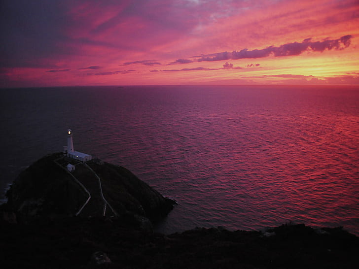 lightened lighthouse on black island near body of water under orange sunset, HD wallpaper