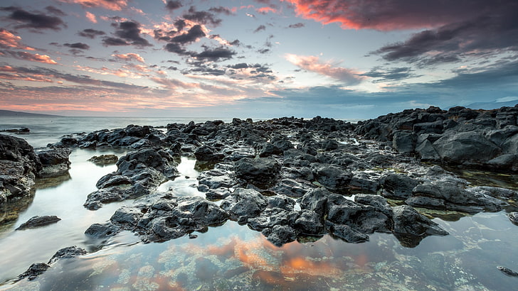 landscape photo of rocks surrounded by body of water during daytime