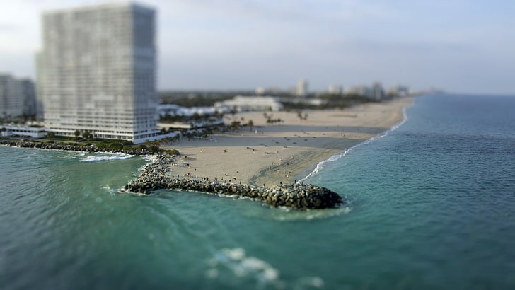 gray concrete building, panoramic photo of gray sand beach near high-rise building