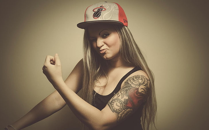 woman in black tank top and Miami Heat cap showing tattoo, blonde