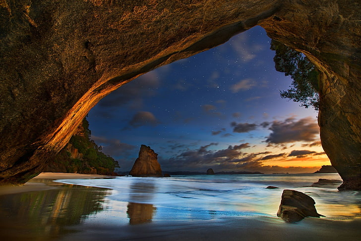 calm body of water under brown cave, beach, sea, sunset, clouds