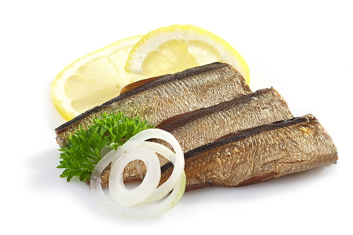 cooked fish with onions, herring, lemon, parsley, white background