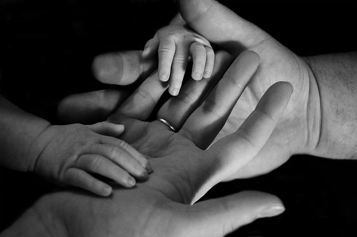 greyscale photography of baby hands touching adult hands, child