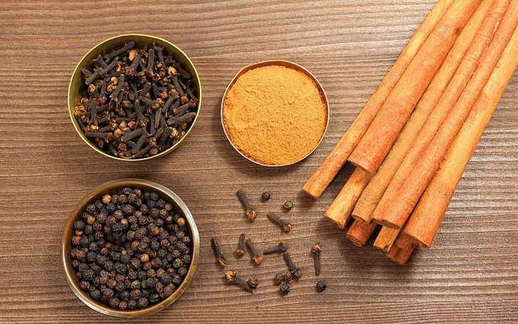 brown cinnamon sticks, spices, table, bowls, cloves, black pepper