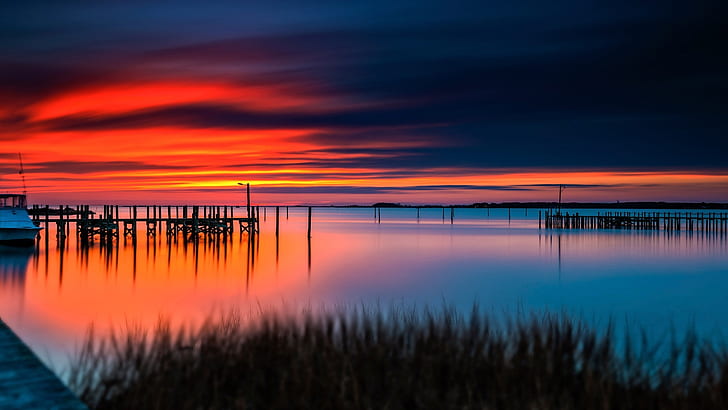 Sunset, red sky, water, boat, dock, blue body of water under orange sunset