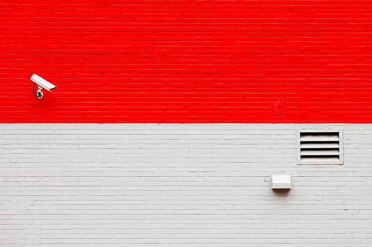 red and white building with white surveillance camera, Banksy