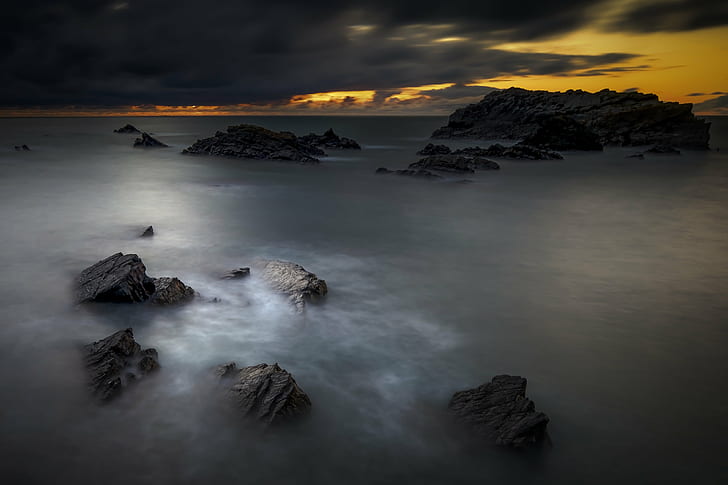 landscape photography of rocks in middle of sea under cloudy sky during daytime
