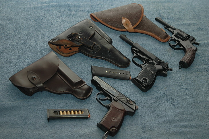 two black semi-automatic pistols and one revolver with holsters