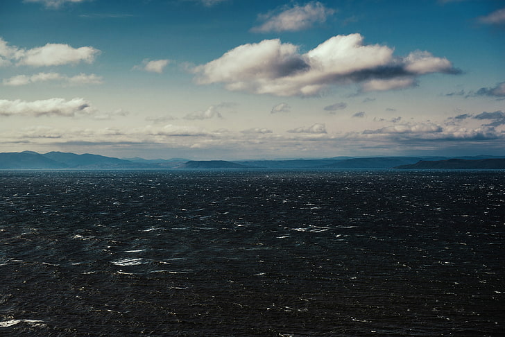 ocean and mountains, aerial shot of land under cloudy sky during daytime