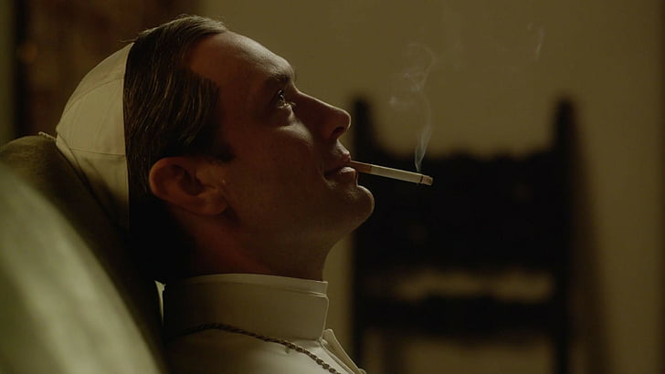 priest sitting on sofa inside room, The Young Pope, Jude Law