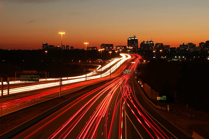 time-lapse photography of vehicle running on road near buildings at golden hour, highway 401, don mills, highway 401, don mills