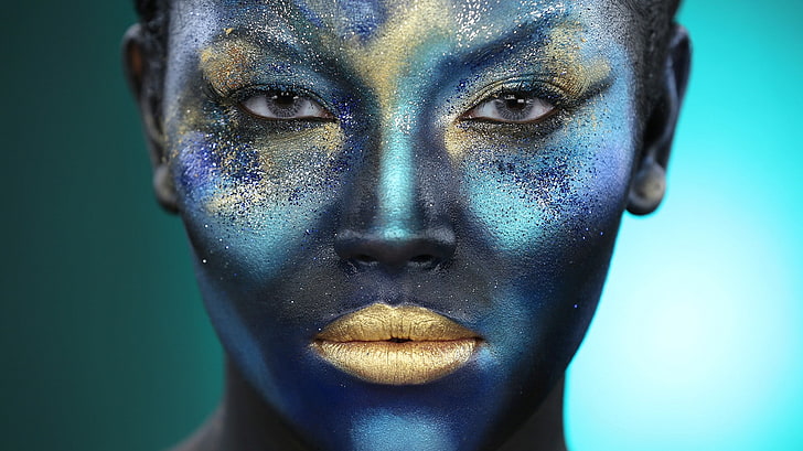 beautiful girl face painted with blue paint with glitter. Stock Photo