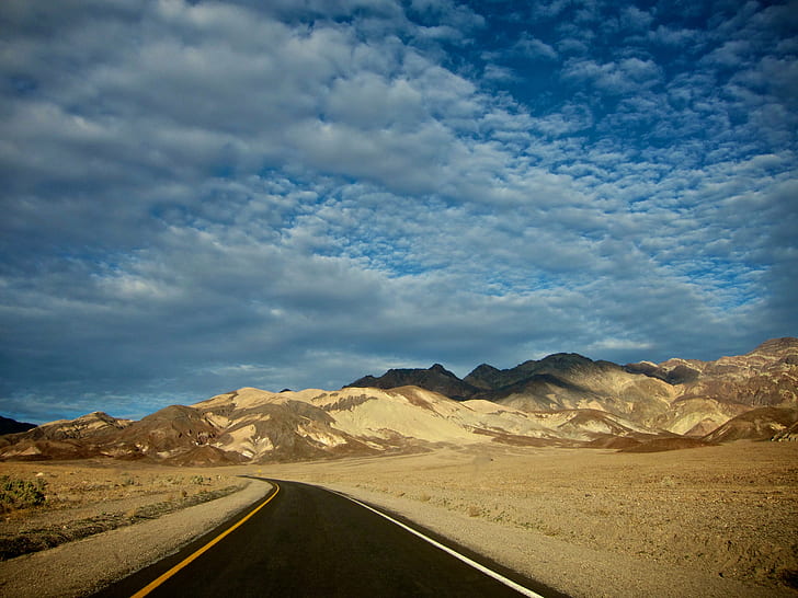 photo of road across mountains during cloudy daytime, bluesky