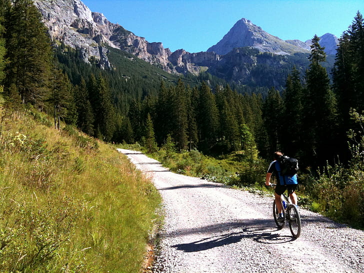 photo of man's riding on bicycle surrounded by trees, scharnitz, achensee, austria, scharnitz, achensee, austria
