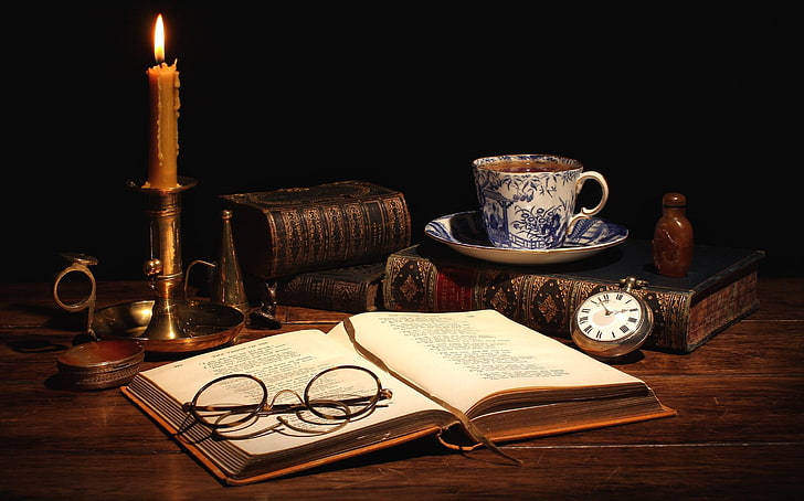 round eyeglasses with black frames, tea, watch, books, candle