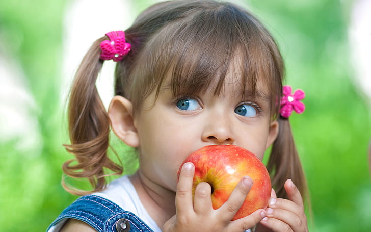 Cute little girl eating apple, girl's blue denim top with red and yellow apple fruit