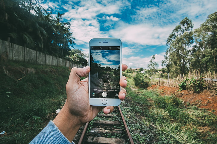 person taking photo of railroad at daytime, phone, hands, landscape