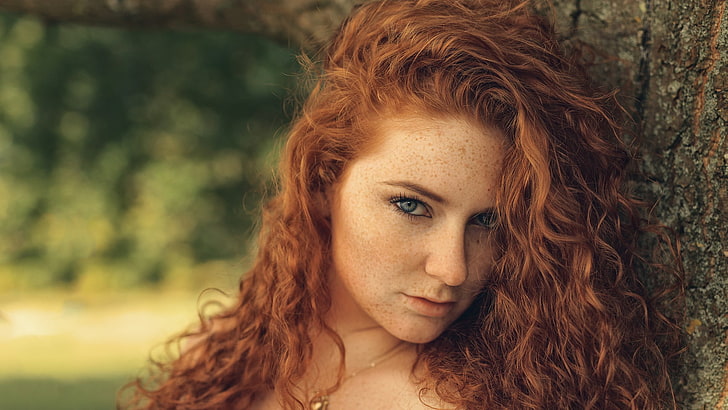 selective focus photography of woman on trunk, redhead, eyes