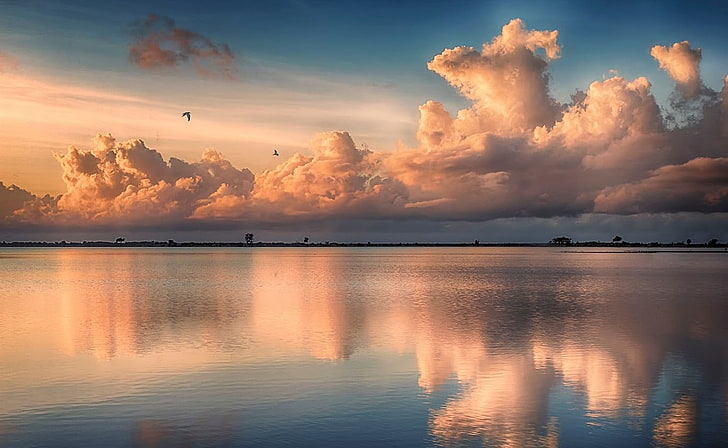 asymmetrical view of calm body of water under clouds, tropical