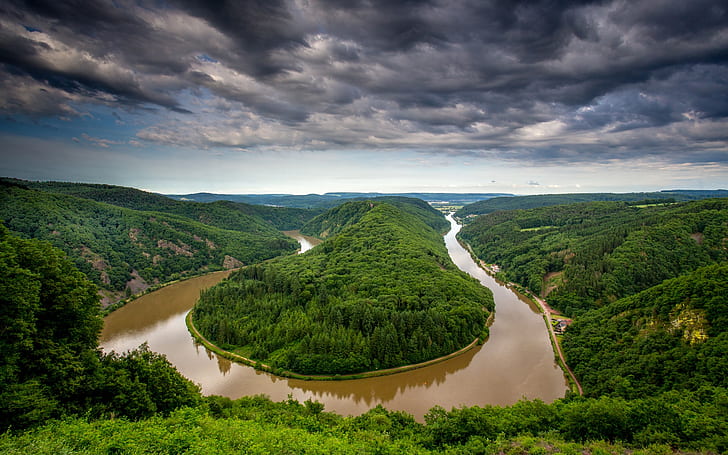 Germany, Saarland, river bend, water after rain, trees, hills