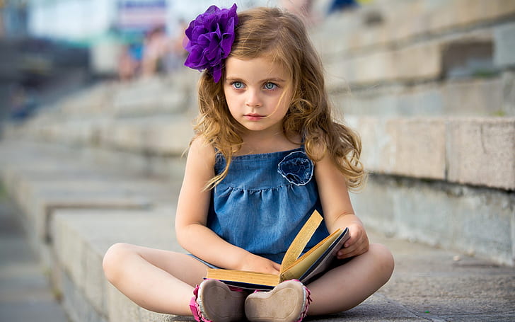 Cute little girl reading a book, girl's blue spaghetti dress