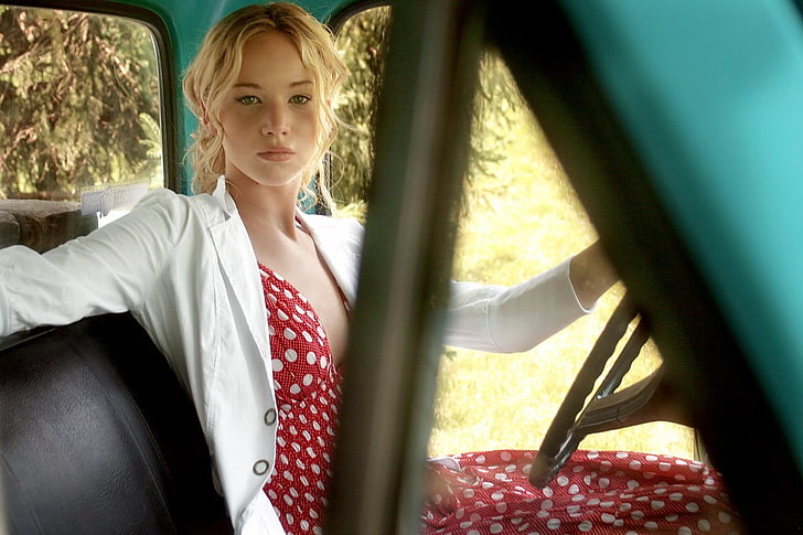 woman in red and white polka-dot dress and white blazer sitting inside vehicle