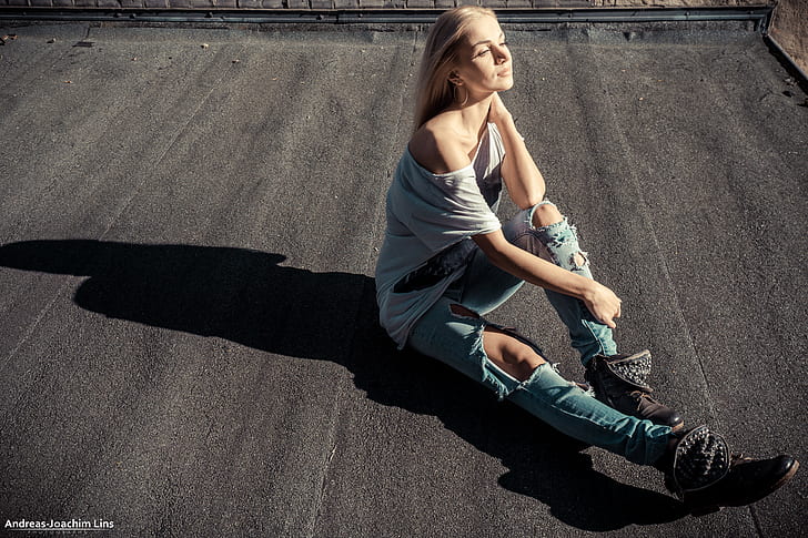 women, blonde, grey shirt, torn jeans, boots, sitting, looking into the distance