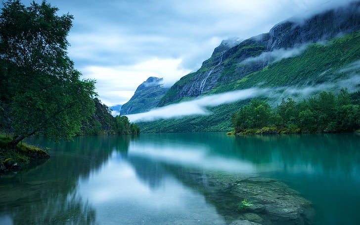 Western Norway, Loen lake surface, Scandinavian mountains, trees, fog, green grass covered mountain and lake