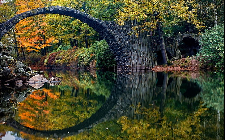 black concrete arch bridge, body of water surrounded by trees
