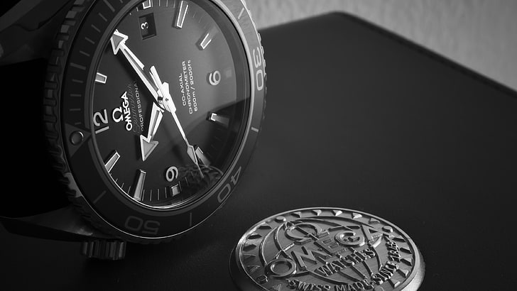 round black Omega analog watch with black leather strap, black analog watch on black tabletop