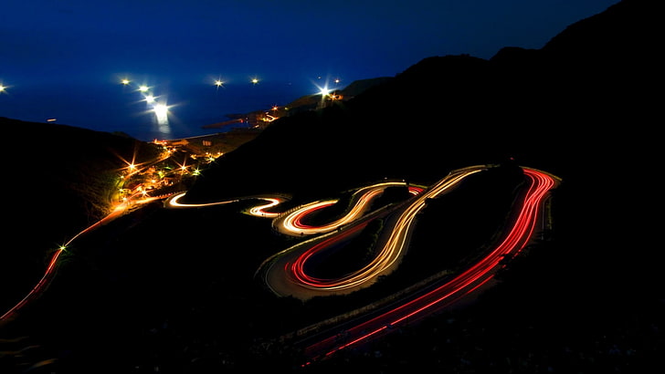 gray pave road, long exposure, hairpin turns, light trails, night