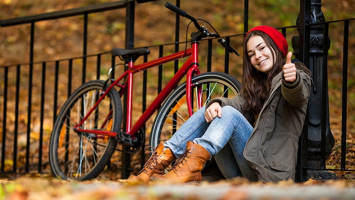 women's brown leather boots, woman in gray coat sitting in front of red bicycle during daytime