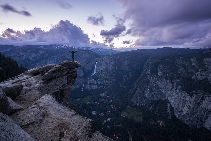 man raising hands on cliff, landscape, clouds, purple, rocks