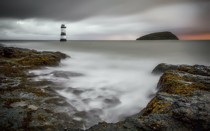 photography of black mountain and lighthouse near body of water, penmon, penmon