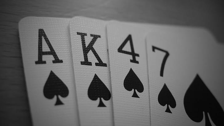 four Ace, King, 4, and 7 of spade playing cards, AK-47, close-up