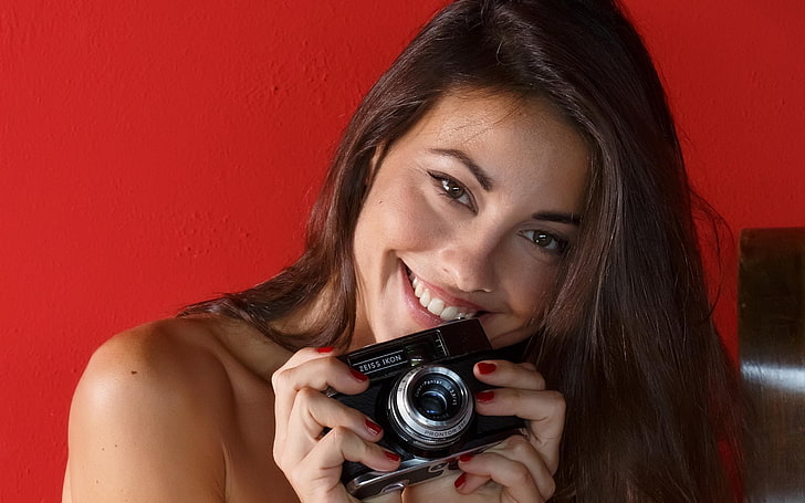 smiling, red background, camera, painted nails, face, Lorena Garcia