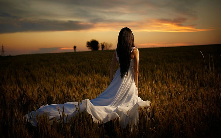 women dark hair white dress field back, sunset, sky, one person