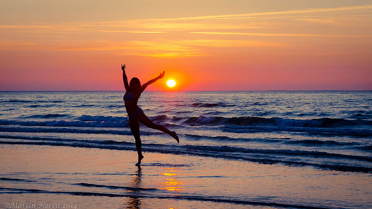 silhouette of woman dancing near seawave during sunset, water