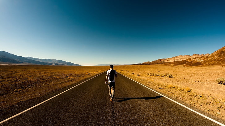 man walking on middle of road surrounded by desert, men, highway