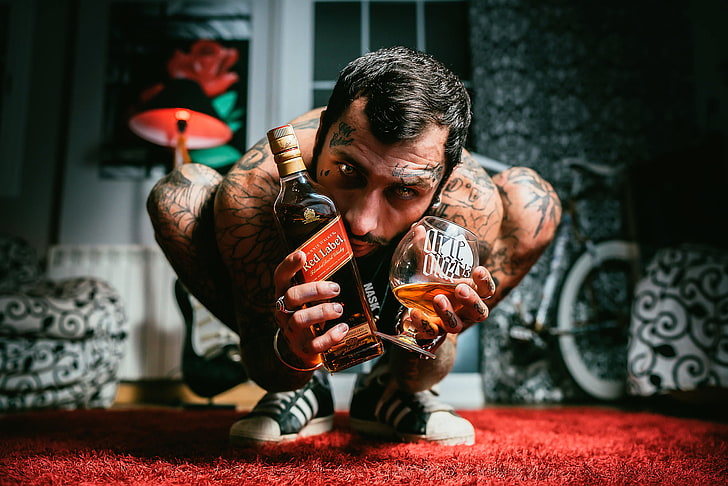 person holding Red Label whisky and snifter glass, bottle, tattoo