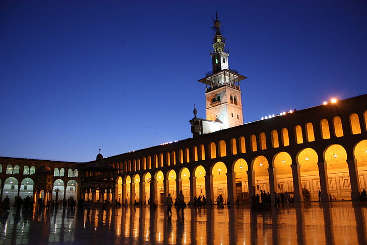 photo of orange lighted concrete building with people standing inside, damascus, umayyad mosque, damascus, umayyad mosque
