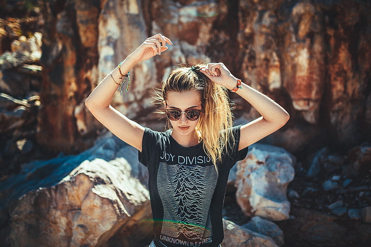 woman wearing black t-shirt and sunglasses beside rock formations