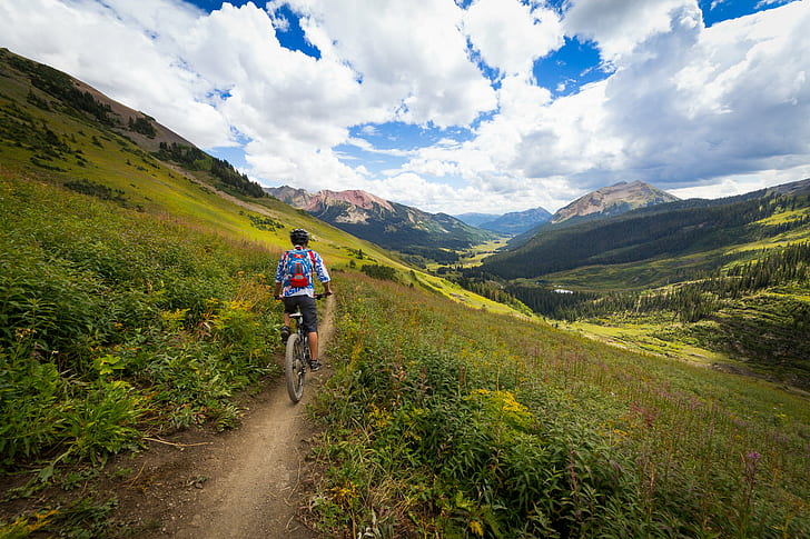 man riding mountain bike on pathway near green grass during daytime, crested butte, crested butte