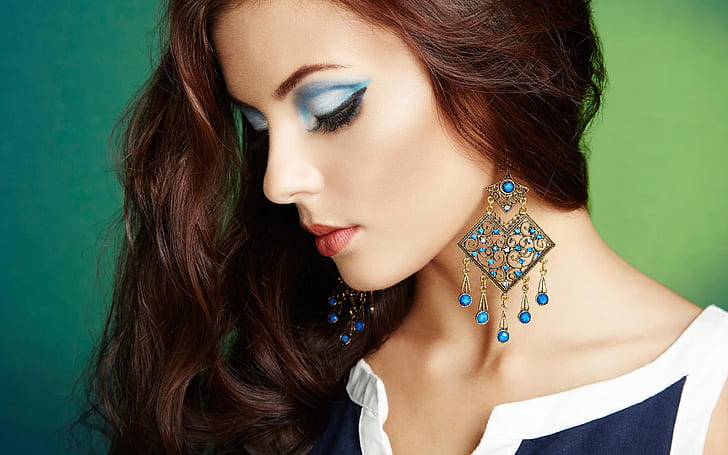 Portrait of beautiful, perfect makeup, fashion girl, women's gold and blue hanging earrings