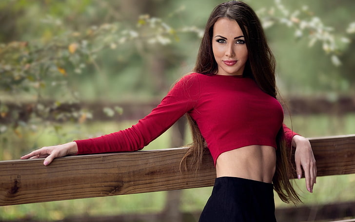 women's red long-sleeved crop top, selective focus photograph of woman leaning on lumber